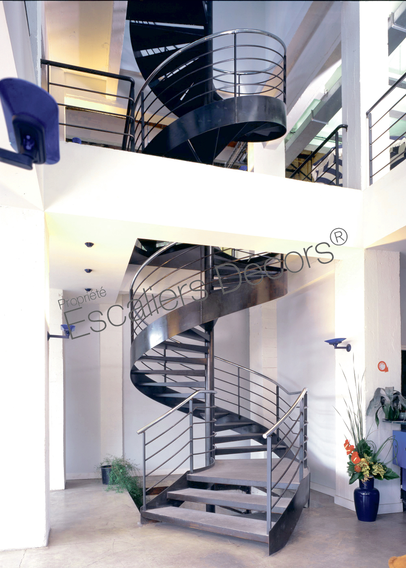Photo DH17 - Collection Loft. Escalier sur mesure en colimaçon avec départ balancé et palier de forme spécifique installé dans des bureaux.